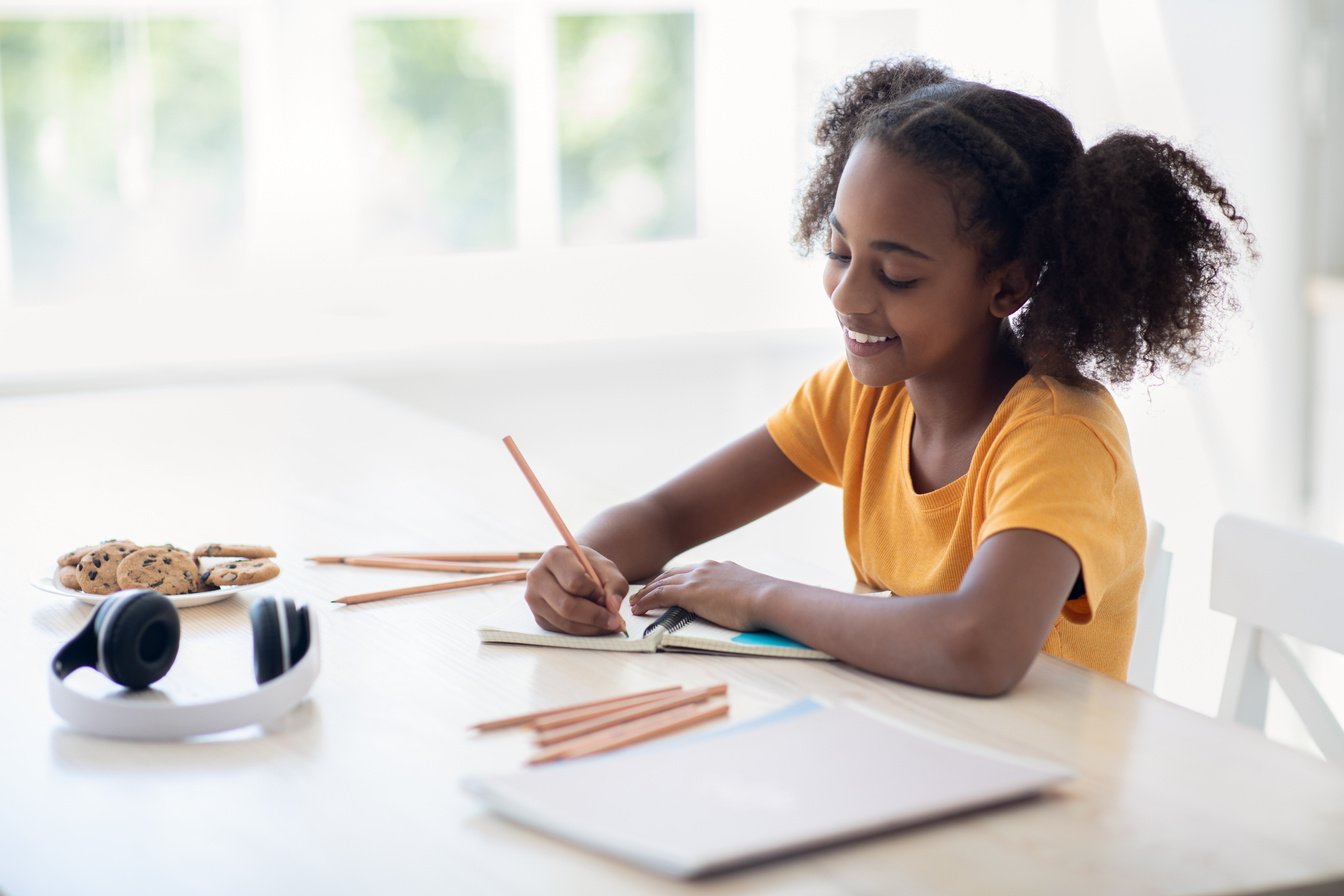 Cute African American Teen Girl Doing Homework at Kitchen